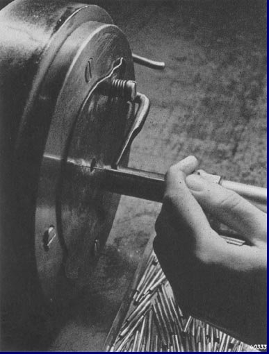 De machine die het eene einde van het kathodebuisje tot een dun pennetje hamert. Foto 1939.